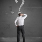 Confused businessman looking at question mark